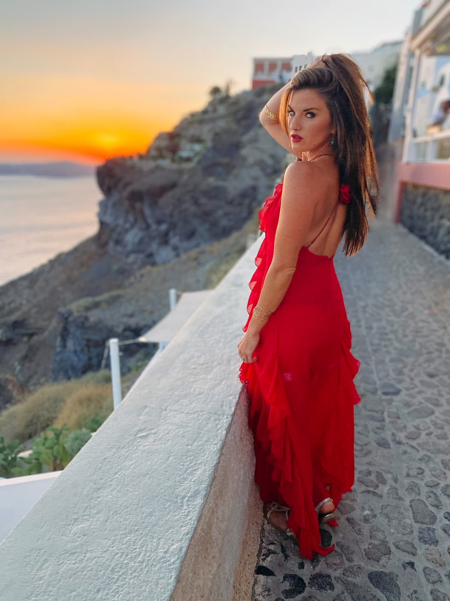 Santorini sunset — red dress on the cliffs